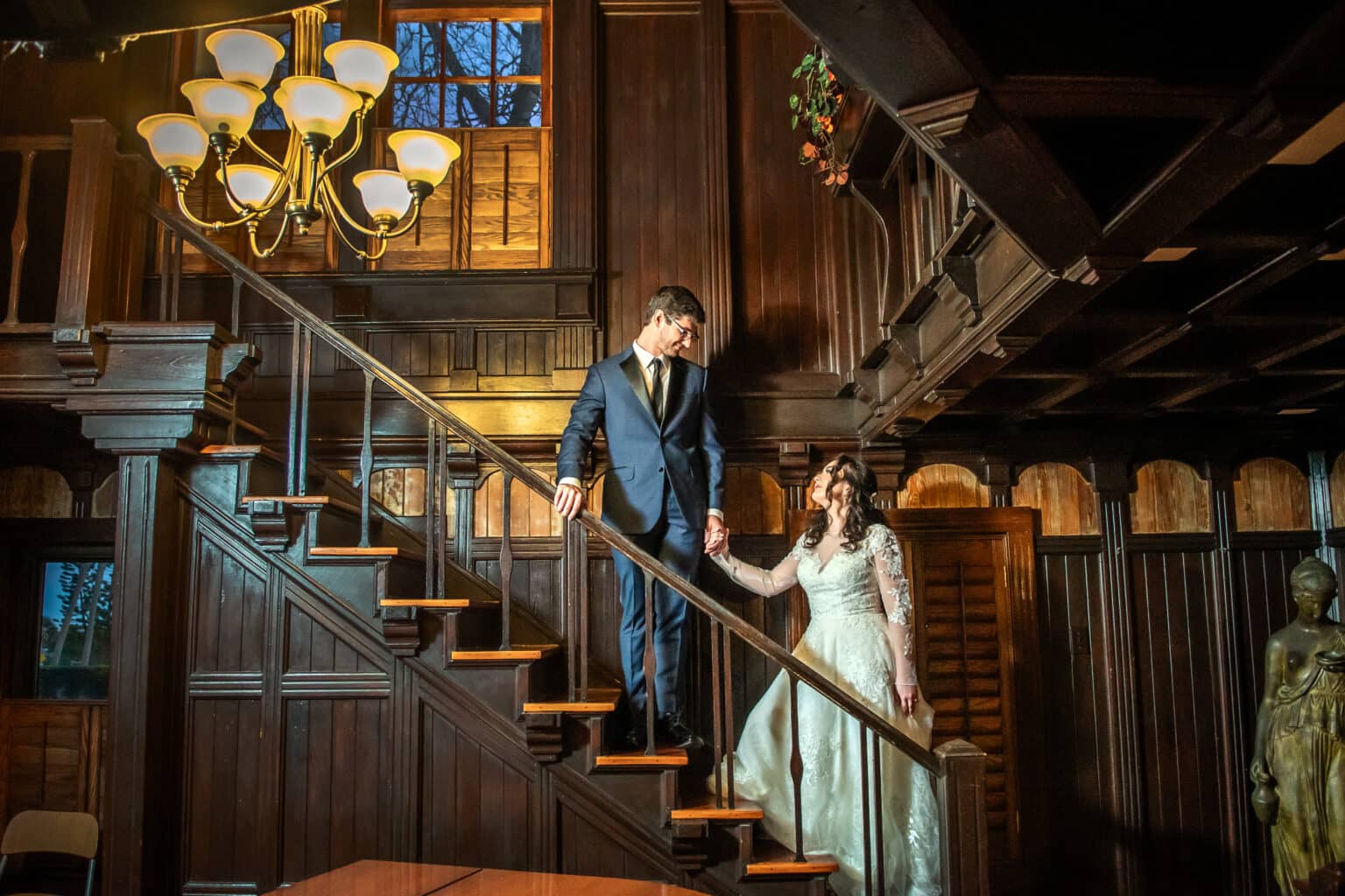 Bride and groom on the historic wooden staircase inside Agatha’s Guesthouse
