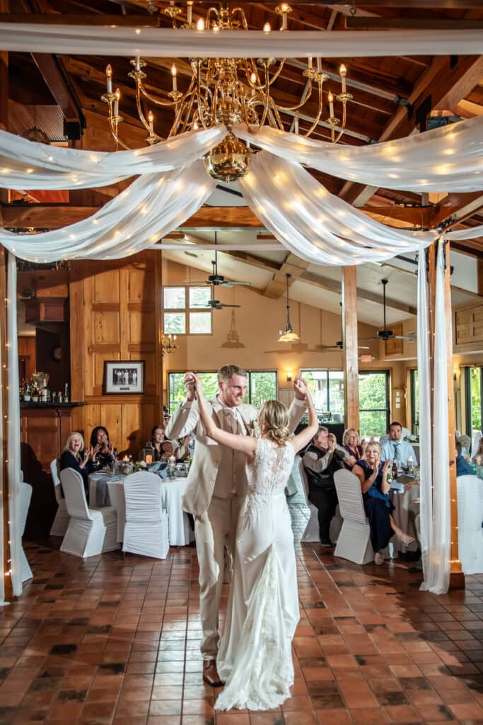 Newlyweds dancing beneath chandeliers and white drapery in The Tavern
