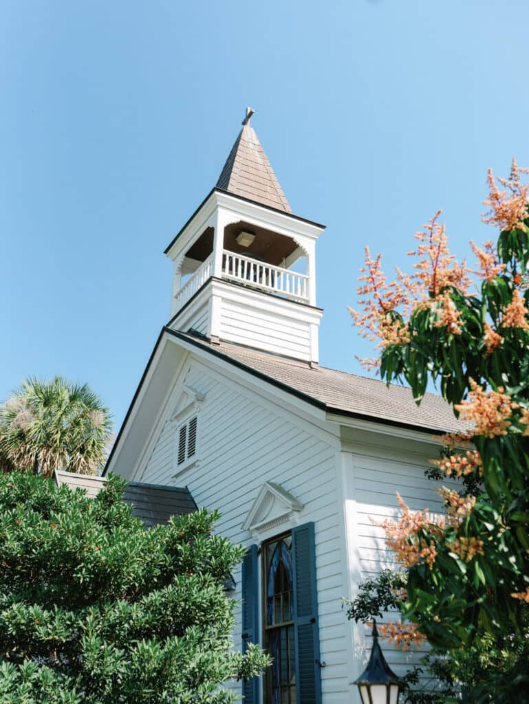 The historic white Chapel framed by palm trees and flowering branches