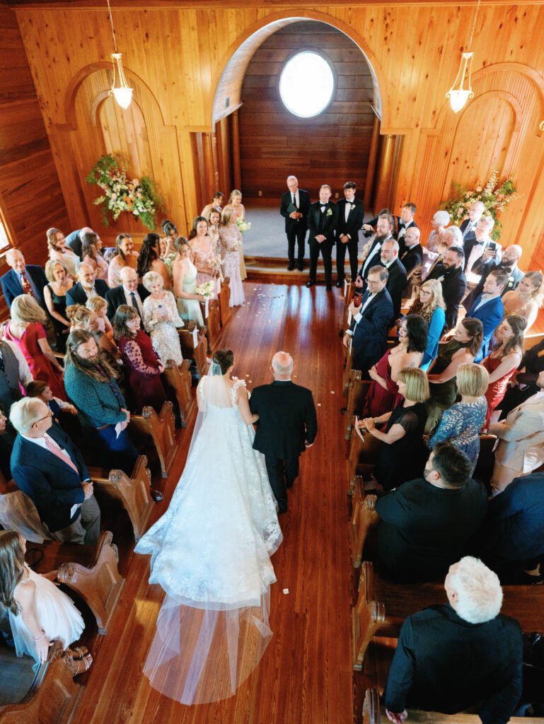 A bride walking down the aisle toward her ceremony inside The Chapel