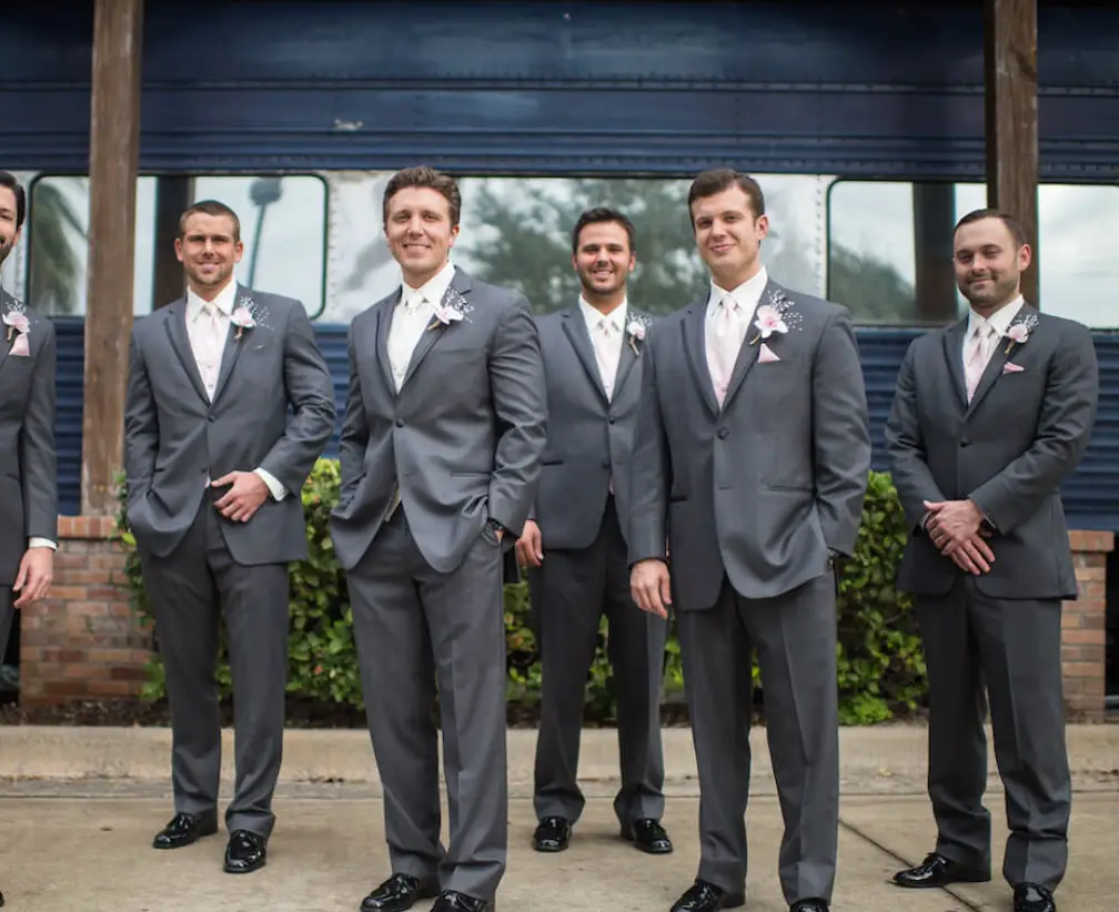 Groom and groomsmen in gray suits outside the historic Club Car