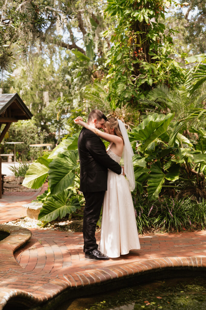 A newlywed couple embracing beside a koi pond in the lush gardens at The Estate on the Halifax